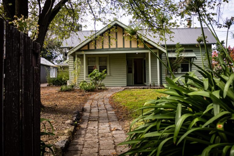 Front view of green weatherboard cottage clinic at 136 Schotters Rd Mernda, with brick path